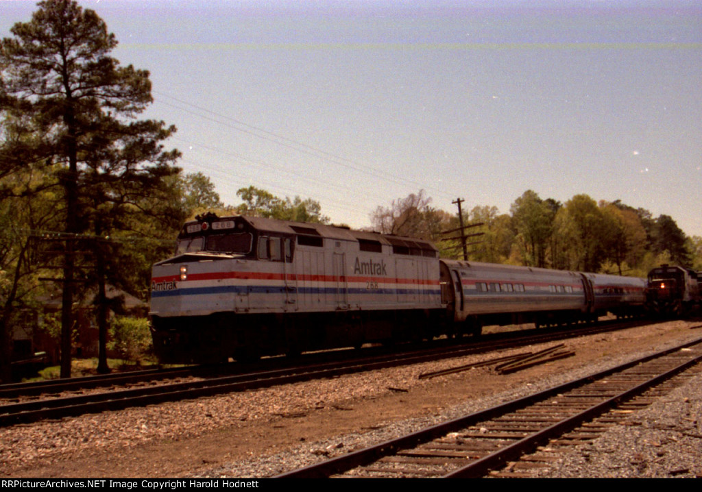 AMTK 268 leads a northbound passenger train past a freight train